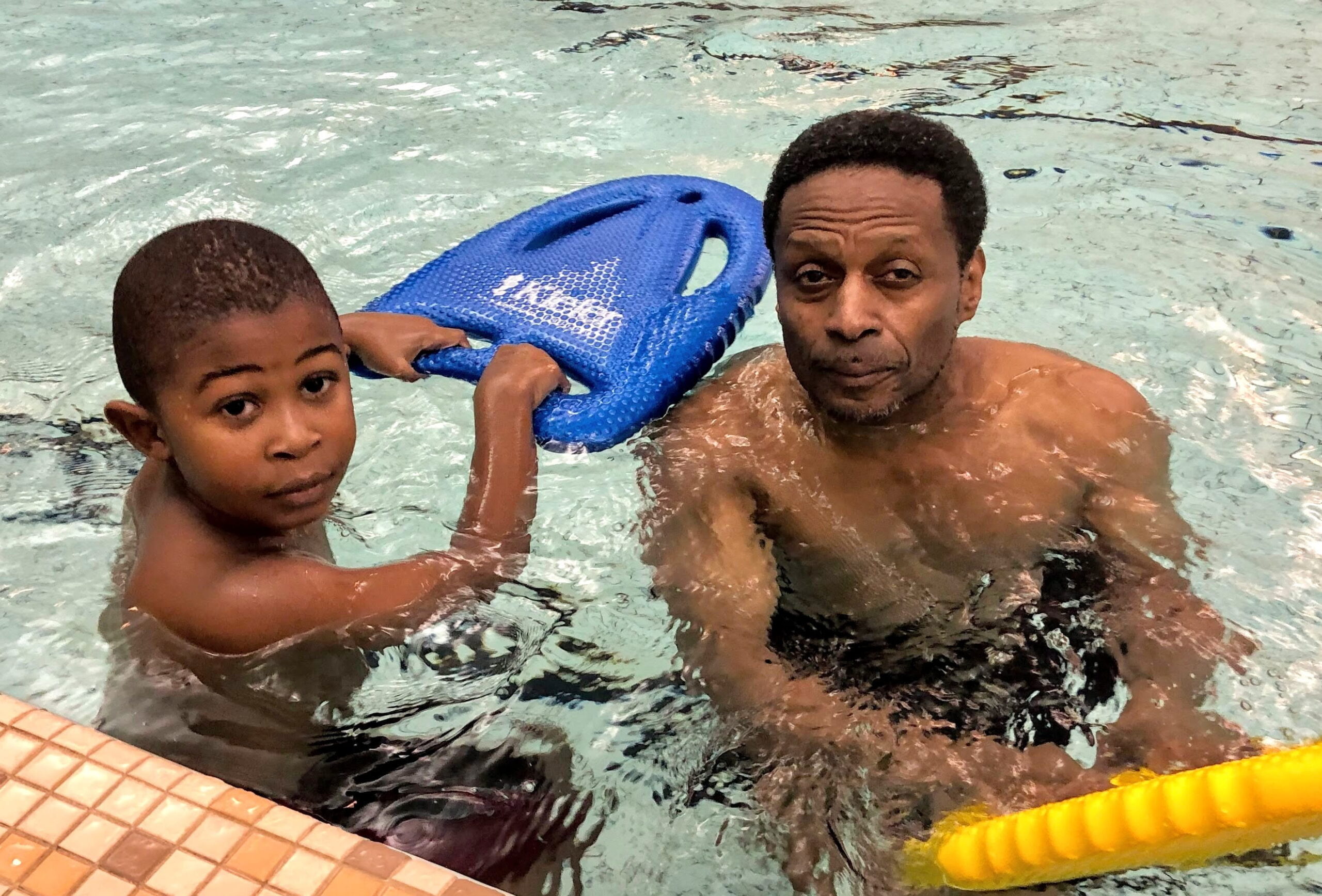 Swimmer with kickboard and grandpa at Saturday Swim School